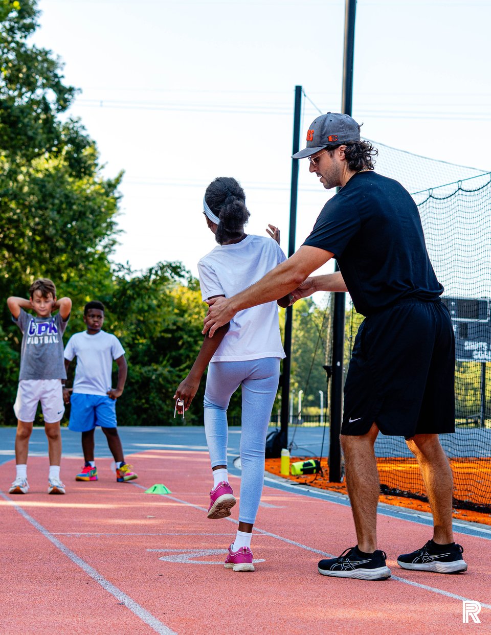 A Jet coach gives an athlete hands-on guidance during an outdoor running drill