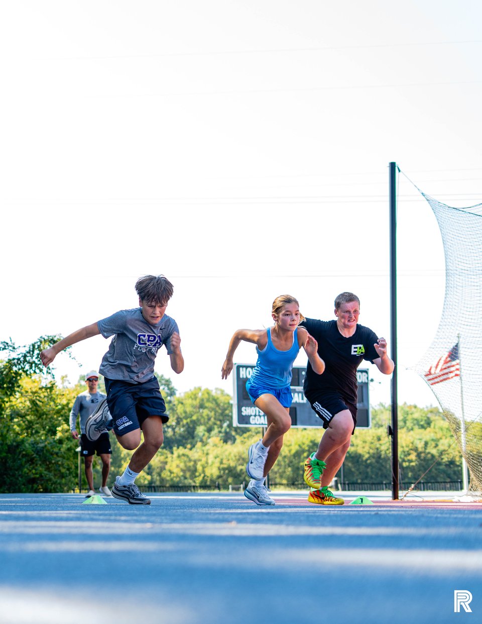 Three athletes accelerate side by side from a start at an outdoor Jet training session