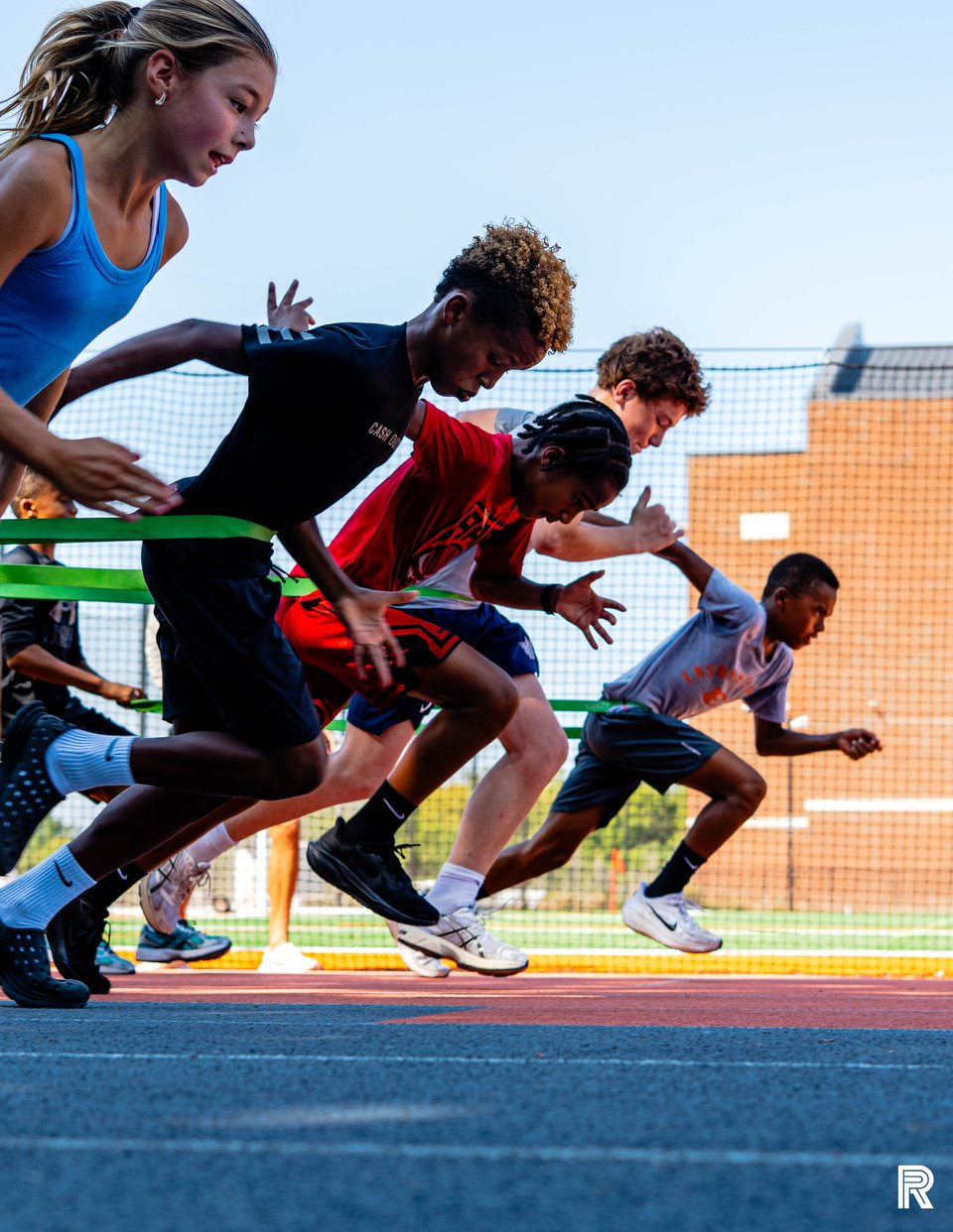 A group of Jet athletes accelerating together from a sprint start on the outdoor track